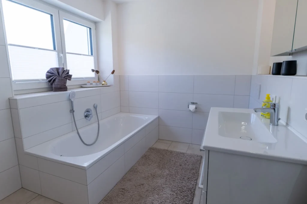 ferienhaus-aura-badezimmer-badewanne-modern Modernes weisses Badezimmer im Ferienhaus Aura mit Badewanne, Handbrause und Waschtisch