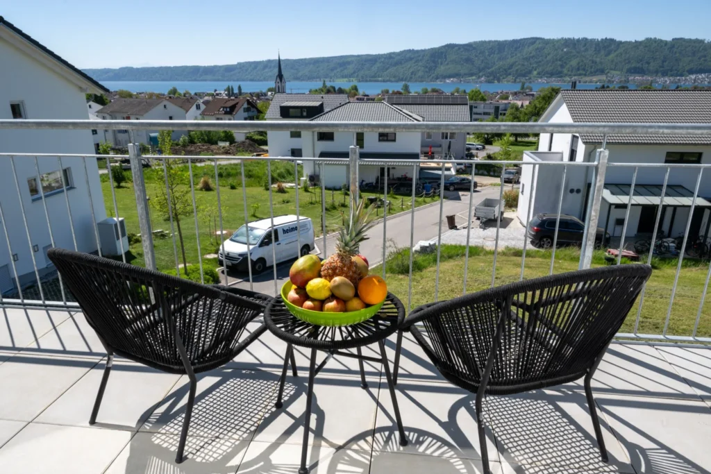ferienhaus-aura-balkon-lounge-seeblick-bodensee Oberer Balkon im Ferienhaus Aura mit Lounge-Stuehlen, Obstschale und weitem Blick ueber den Bodensee
