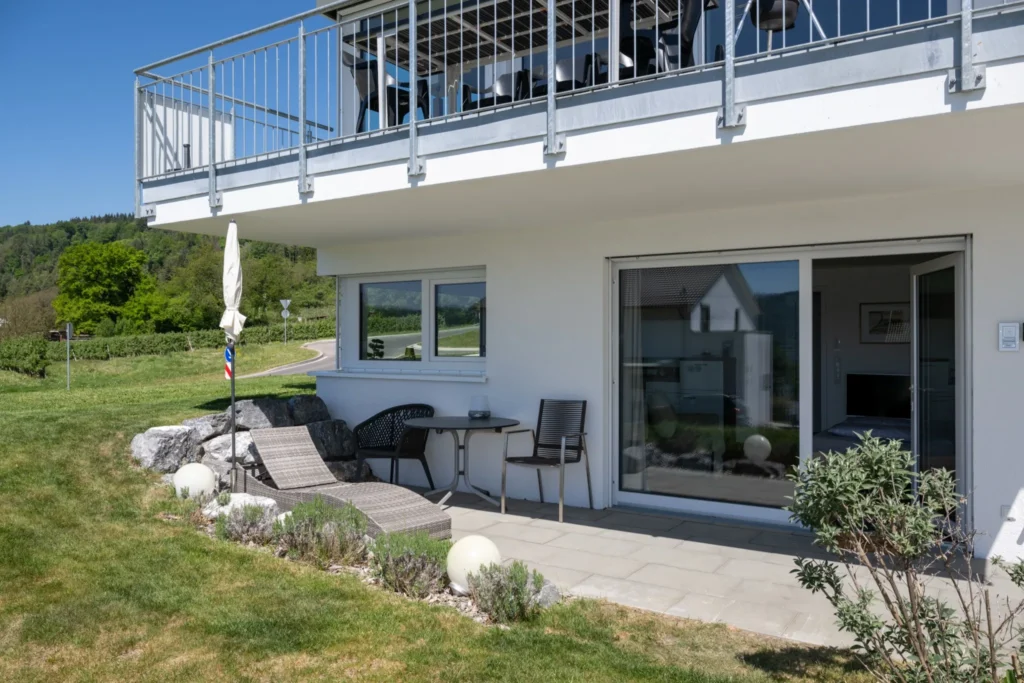 ferienhaus-aura-erdgeschoss-terrasse-garten Erdgeschoss-Terrasse des Ferienhaus Aura mit Sonnenliege, Gartenmoebeln und Blick auf Weinberge