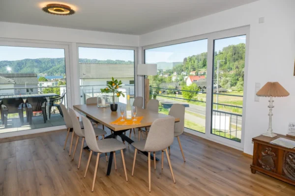 Essbereich im Ferienhaus Aura mit 8-Personen-Esstisch, Eck-Panoramafenstern und Blick auf See und Berge