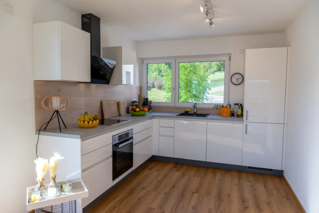 ferienhaus-aura-kueche-modern-einbaukueche Moderne weisse Einbaukueche im Ferienhaus Aura mit Backofen, Dunstabzug und Blick ins Gruene