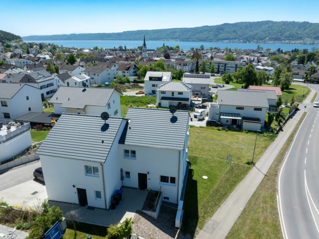 ferienhaus-aura-luftaufnahme-bodensee-panorama Panorama-Luftaufnahme des Ferienhaus Aura mit weitem Blick auf den Bodensee, Kirche und das Dorf