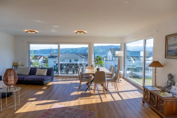 Lichtdurchfluteter Wohnbereich im Ferienhaus Aura mit Panoramafenstern und Bodensee-Blick ueber die Daecher