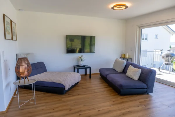 Gemuetliches Wohnzimmer im Ferienhaus Aura mit L-foermigem Sofa, Wandfernseher und direktem Balkonzugang